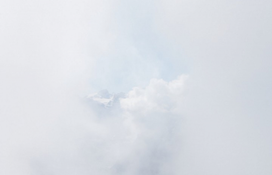 Ein Nebelbild. In der Mitte sieht man leicht verschleiert einen Bergspitz