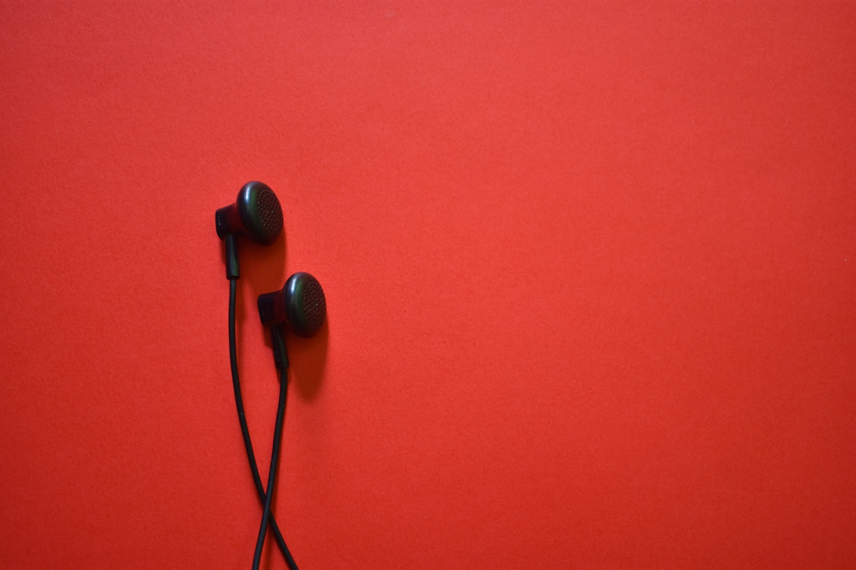 Zwei schwarze Kopfhörer Plugs mit Kabel vor rotem Hintergrund