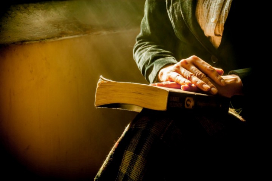 Zu sehen ist, wie eine ältere Person eine alte Bibel auf ihrem Schoss hält