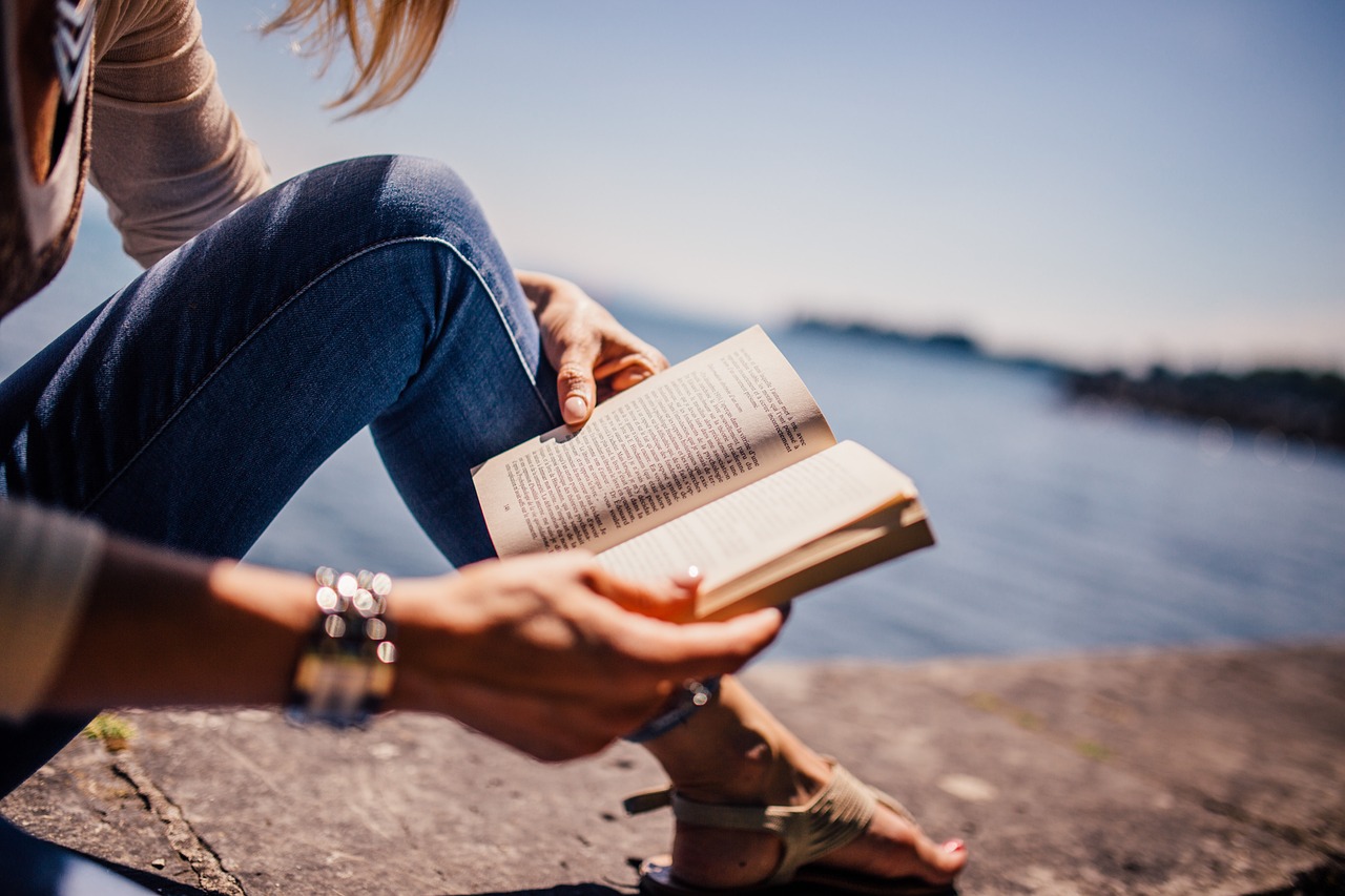 Eine junge Frau liest ein Buch am Meer